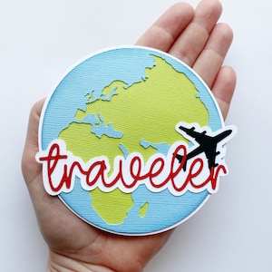 May include: A blue and green paper craft of the world with a red and white paper craft word "traveler" and a black paper craft airplane.