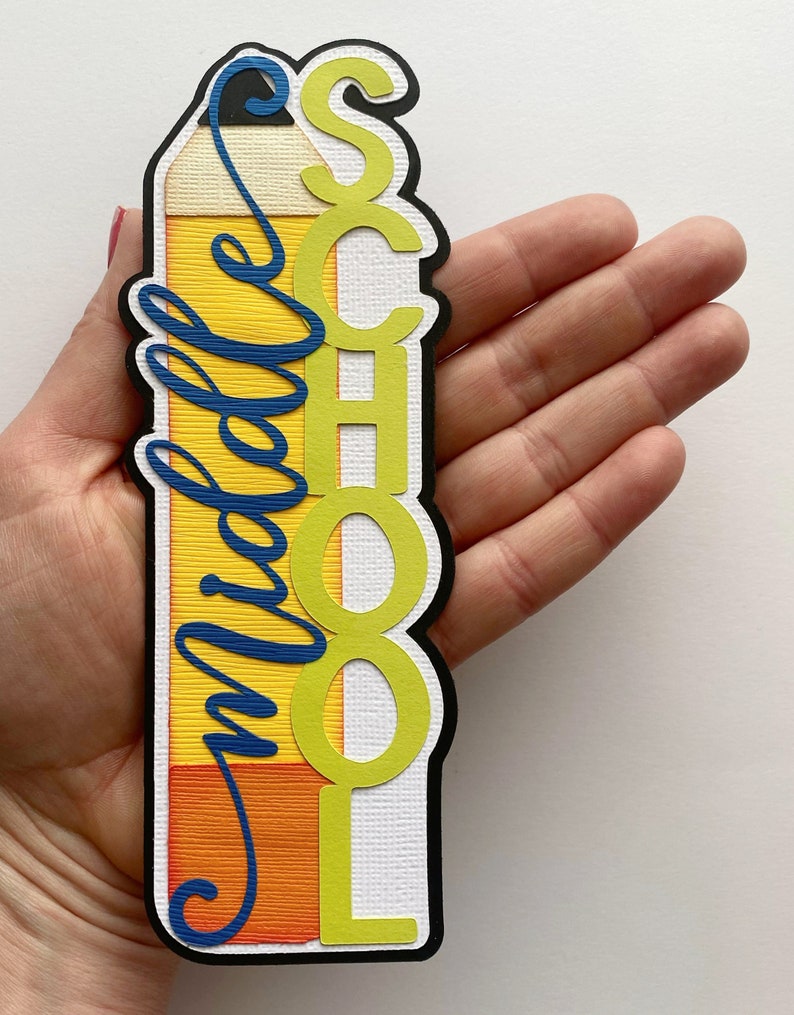 May include: A yellow pencil-shaped bookmark with the word "School" in green letters and the word "middle" in blue cursive writing.