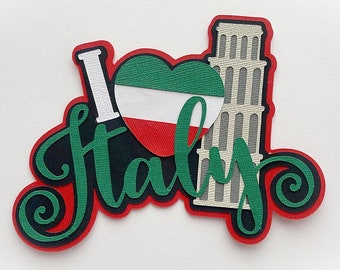 Puede incluir: Una decoración de papel recortado en capas que presenta el texto blanco I, un corazón con los colores de la bandera italiana con franjas horizontales verde, blanca y roja, y el texto cursivo verde Italy, junto a una ilustración gris de la Torre de Pisa.