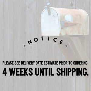 May include: A white mailbox with a rusty patina, mounted on a wooden fence. The mailbox has a sign that reads "NOTICE. PLEASE SEE DELIVERY DATE ESTIMATE PRIOR TO ORDERING 4 WEEKS UNTIL SHIPPING."