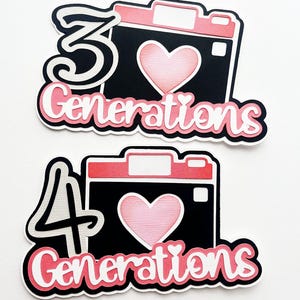 May include: Two black and white camera-shaped decorations with pink hearts and the text "Generations" in pink. The first decoration has the number "3" in white and the second decoration has the number "4" in white.