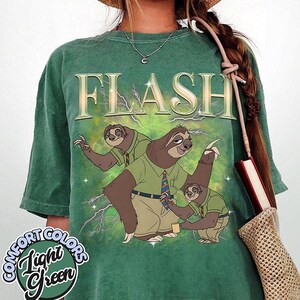 May include: Light green Comfort Colors t-shirt featuring a cartoon illustration of three sloths in office attire with the word "FLASH" above them. The shirt has a vintage, washed look.