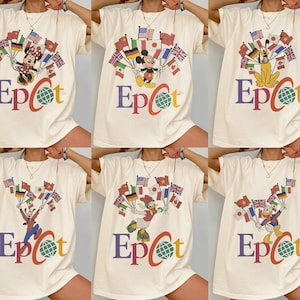 May include: Cream-coloured t-shirts featuring Disney characters holding flags of various countries. The word "Epcot" is printed in colourful letters below the characters, with a globe graphic.