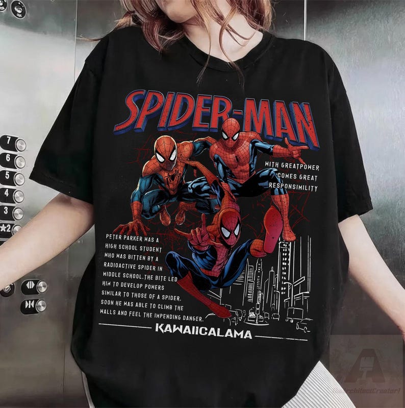May include: Black t-shirt featuring three Spider-Man illustrations in red, blue, and black. The text "SPIDER-MAN" is in red and blue, with additional text describing the character's origin. The shirt also includes the text "KAWAIICALAMA".