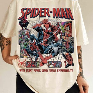 K&ouml;nnte beinhalten: Elfenbeinfarbenes Spider-Man-T-Shirt mit Comic-Grafik. Das Design zeigt den Schriftzug "SPIDER-MAN" in Rot und verschiedene Bilder von Spider-Man. Der Text "WITH GREAT POWER COMES GREAT RESPONSIBILITY" ist ebenfalls enthalten.