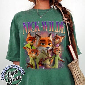 Puede incluir: Camiseta verde claro con un dise&ntilde;o de Nick Wilde de Zootopia. El dise&ntilde;o incluye el texto "NICK WILDE" en una fuente degradada y varios zorros de dibujos animados. La camiseta tambi&eacute;n tiene el texto "COMFORT COLORS Light Green".