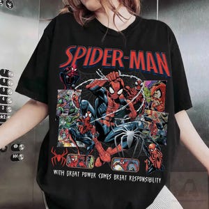 K&ouml;nnte beinhalten: Schwarzes T-Shirt mit einem Spider-Man-Comic-Design. Das Design zeigt die Worte "SPIDER-MAN" in Rot und Blau, verschiedene Spider-Man-Illustrationen und den Satz "WITH GREAT POWER COMES GREAT RESPONSIBILITY."