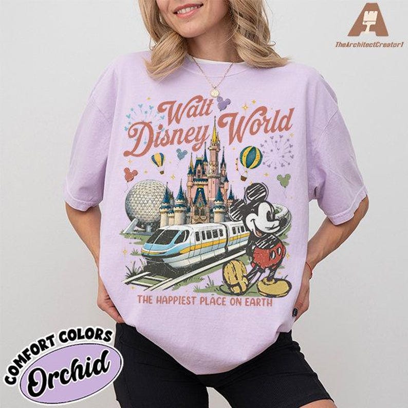 May include: Orchid-colored Comfort Colors t-shirt featuring a Walt Disney World graphic. The design includes a castle, monorail, Mickey Mouse, and the text "The Happiest Place on Earth."