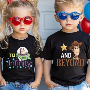 May include: Two children wearing black t-shirts with cartoon graphics. One shirt says "To Infinity" with Buzz Lightyear, the other says "And Beyond" with Woody. Both children wear sunglasses, one red, one blue.