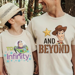 May include: Two beige t-shirts with cartoon graphics. One shirt features Buzz Lightyear in a spaceship with the text "To Infinity". The other shirt has Woody with the text "And Beyond" and a gold star.