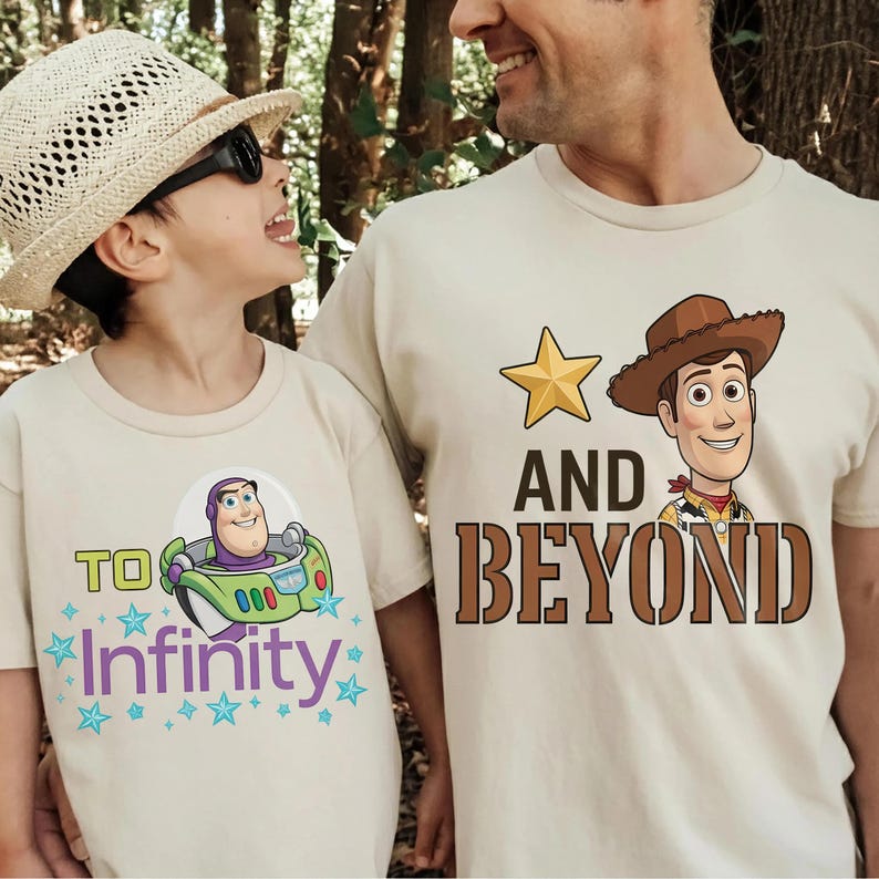 May include: Two beige t-shirts with cartoon graphics. One shirt features Buzz Lightyear in a spaceship with the text "To Infinity". The other shirt has Woody with the text "And Beyond" and a gold star.