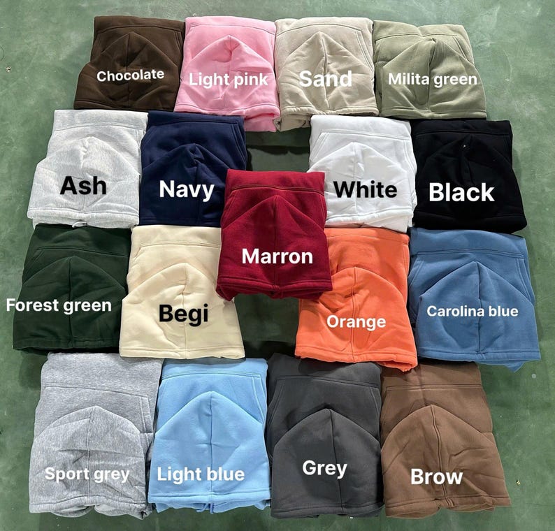 May include: A collection of folded hoodies in various colors, including chocolate, light pink, sand, and milita green. Other colors are ash, navy, white, black, forest green, begi, marron, orange, carolina blue, sport grey, light blue, grey, and brow.