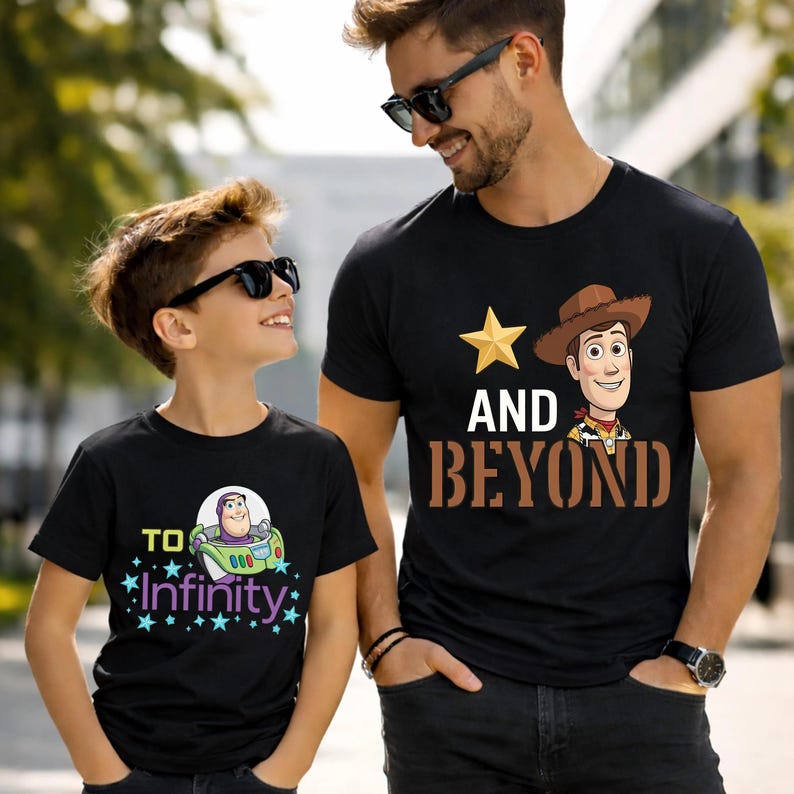 May include: Two black t-shirts with cartoon graphics. One shirt features Buzz Lightyear in a spaceship with the text "To Infinity". The other shirt has Woody with the text "And Beyond". Both shirts are worn by people.