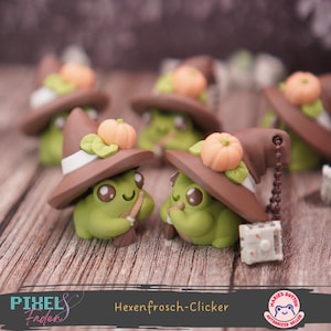 Könnte beinhalten: Mehrere grüne Froschfiguren mit braunen Hexenhüten, verziert mit orangefarbenen Kürbissen und grünen Blättern. Die Figuren halten kleine Besen. Der Text "Hexenfrosch-Clicker" ist unten im Bild zu sehen.