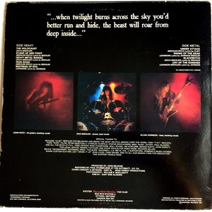May include: Back cover of a vinyl record by the heavy metal band Exciter. The album cover features a black and white photo of the band members. The album title is "Heavy Metal Maniac" and the album's release date is 1983. The album's tracklist is listed on the back cover. The album's credits are also listed on the back cover.