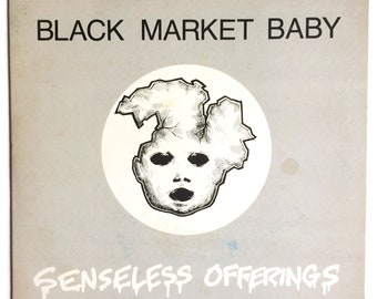 May include: Black and white album cover with the title "Black Market Baby" and the text "Senseless Offerings" in a stylized font. The cover features a drawing of a baby's face with a cracked head.