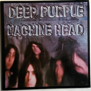 May include: A vintage vinyl record album cover featuring the band Deep Purple. The album title "Machine Head" is printed in large, bold letters across the front of the cover. The band members are pictured in a blurry, out-of-focus image behind the title.