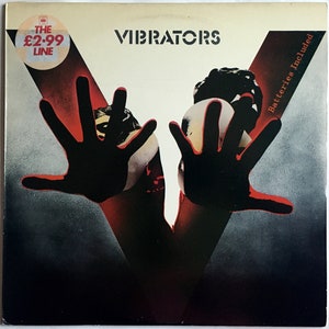 May include: A black and white album cover with the band name "Vibrators" in white text. The cover features a red and black image of two hands reaching out, with the text "Batteries Included" in white text on the right side.