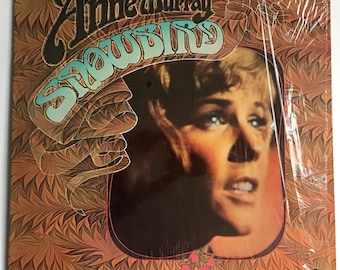 May include: A vintage vinyl record album cover featuring a close-up portrait of Anne Murray. The album title "Snowbird" is written in a stylized font with a blue and gold background.