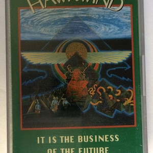 May include: A green cassette tape with a colorful image of a winged sun and a pyramid. The text "HAWKWIND" is at the top of the image and the text "IT IS THE BUSINESS OF THE FUTURE TO BE DANGEROUS" is at the bottom.