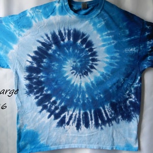 May include: A blue and white tie-dye t-shirt with a spiral design. The shirt is a 2X-Large size and has the code TD-26.