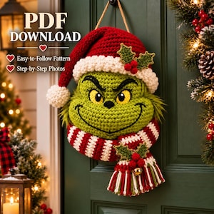 May include: A crochet wall hanging featuring a green character with yellow eyes, wearing a red and white Santa hat and a red and white striped scarf. The design includes holly leaf accents with red berries and text reading PDF DOWNLOAD.