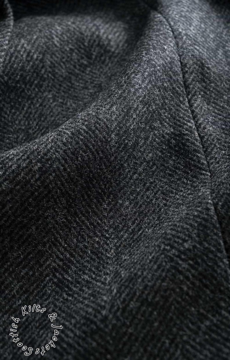 May include: Close-up of a dark gray herringbone fabric. The material has a textured surface with a diagonal weave pattern. The fabric is likely wool or a wool blend, suitable for jackets or coats. The words "Scottish Kilts & Jackets" are visible.