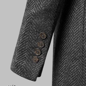 May include: Close-up of a dark gray herringbone tweed jacket sleeve with four brown buttons. The jacket has a classic design and is likely part of a formal wear collection. The image also includes a Scottish emblem and the words "Scottish Kilts & Jackets".