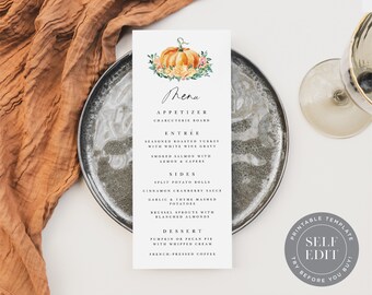 May include: A rectangular menu card featuring a pumpkin and floral design. The menu lists various courses, including appetizers, entrées, sides, and desserts. The card is placed on a grey plate, with a brown cloth and a wine glass in the background.