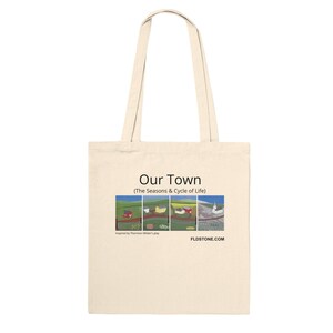 May include: Cream-colored tote bag with the text "Our Town" and a colorful landscape design. The design features four panels depicting scenes with houses, fields, and a church. The bag has two handles for carrying.