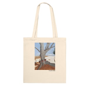 Puede incluir: Una bolsa de tela con un fondo de lona beige y una imagen impresa de un árbol con tres macetas marrones en su base. La imagen se coloca sobre un fondo de paisaje nevado con un cielo azul. El texto "FLDSTONE" está impreso en negro en la parte inferior de la imagen.