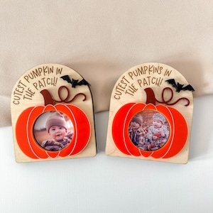 May include: Two wooden pumpkin-shaped photo frames with orange acrylic accents. Each frame has a photo of a baby and the text "Cutest Pumpkins in the Patch!". Black bat cutouts are at the top.