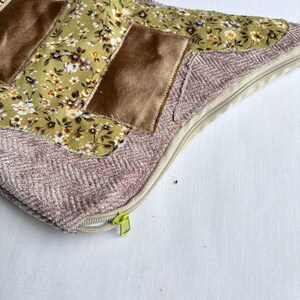 K&ouml;nnte beinhalten: Ein dekoratives Kissen mit floralem Muster und braunen Samtakzenten. Das Kissen hat einen hellgr&uuml;nen floralen Stoff, braune Samtflecken und einen rosa Fischgr&auml;tenrand. Ein beigefarbener Rei&szlig;verschluss mit gr&uuml;nem Zipper ist sichtbar.