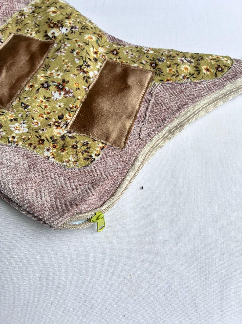 K&ouml;nnte beinhalten: Ein dekoratives Kissen mit floralem Muster und braunen Samtakzenten. Das Kissen hat einen hellgr&uuml;nen floralen Stoff, braune Samtflecken und einen rosa Fischgr&auml;tenrand. Ein beigefarbener Rei&szlig;verschluss mit gr&uuml;nem Zipper ist sichtbar.