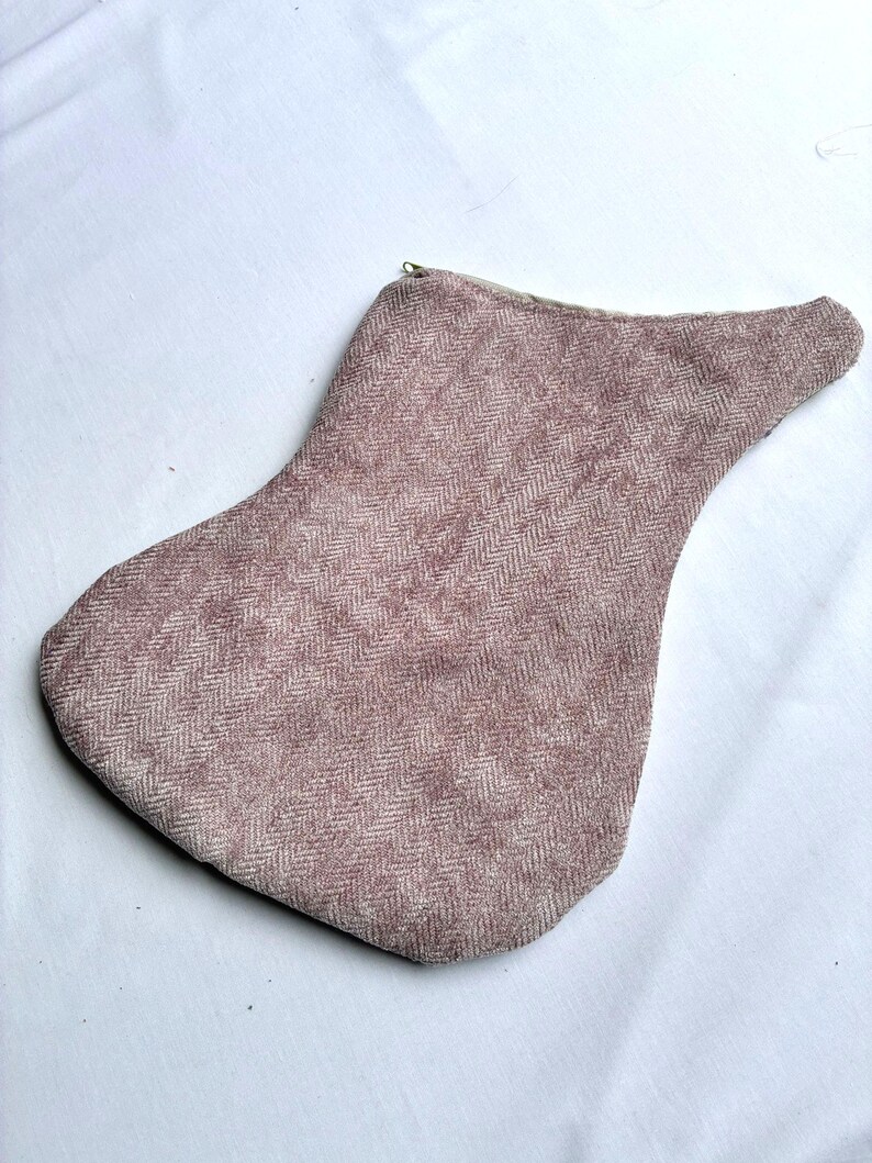K&ouml;nnte beinhalten: Eine mauvefarbene, tropfenf&ouml;rmige Tasche mit Fischgr&auml;tenmuster. Die Tasche hat einen Rei&szlig;verschluss und ist aus einem strukturierten Stoff gefertigt. Das Design ist schlicht und elegant, geeignet f&uuml;r verschiedene Zwecke.