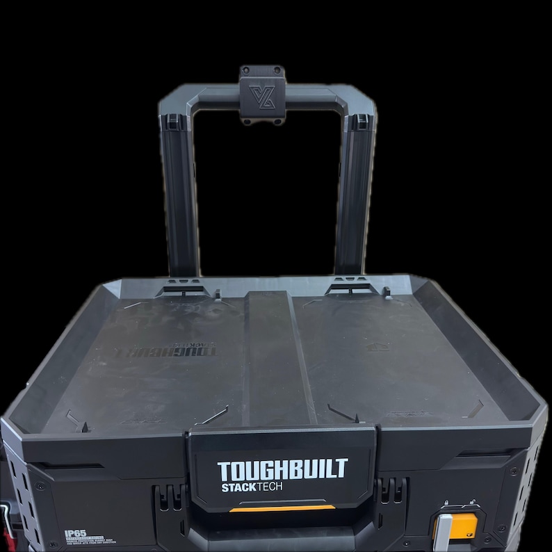 以下が含まれることがあります： 黒いToughBuilt StackTechツールボックス。長方形の収納コンパートメントと上部ハンドルを備えています。前面には白い文字でToughBuilt StackTechとIP65のラベルが表示されています。頑丈なフレームとロック機構を備えた設計です。