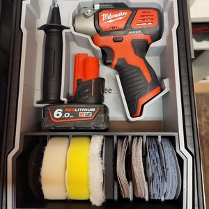 Pode incluir: Um inserto de plástico preto e cinza para maleta de ferramentas contendo uma ferramenta elétrica sem fio Milwaukee M12, uma bateria Redlithium de 6.0 Ah, um cabo preto e uma fileira de vários discos circulares de espuma para polimento e lixamento.