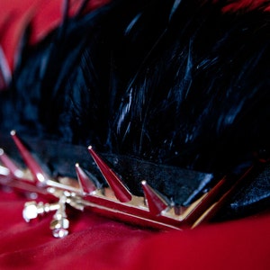 May include: A black feather clutch with silver spikes and a silver clasp.