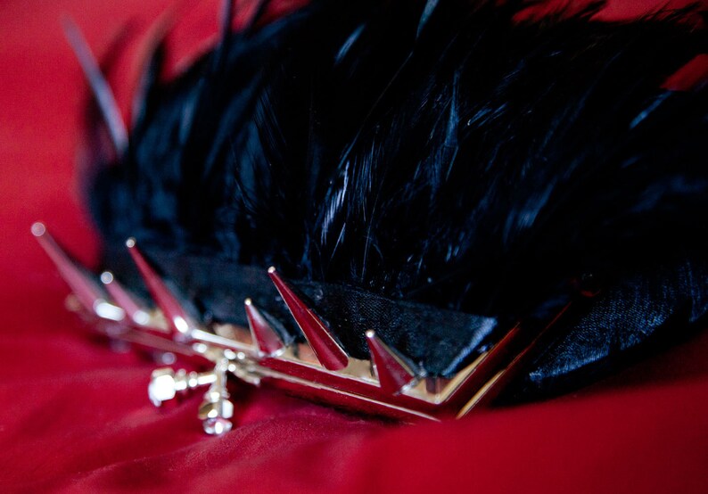 May include: A black feather clutch with silver spikes and a silver clasp.