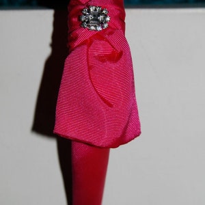 May include: A pink fabric headband with a rhinestone embellishment.