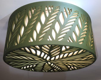 May include: A cylindrical olive green ceiling light fitting featuring a laser-cut leaf pattern that allows light to shine through the cutouts. The design covers both the side and the bottom circular panel of the lamp shade.