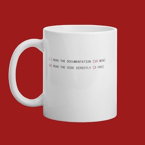 Puede incluir: Taza de cerámica blanca con un asa grande. La taza presenta texto en negro y rojo: "[] READ THE DOCUMENTATION (15 MIN)" y "[X] READ THE CODE DIRECTLY (3 HRS)". La taza está sobre un fondo rojo liso.