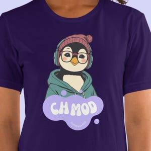 May include: A navy blue t-shirt featuring a cartoon penguin wearing glasses, a pink beanie, and headphones. The penguin is wearing a teal hoodie. Below the penguin is a purple speech bubble with the text "CH MOD" and "Softwear404".