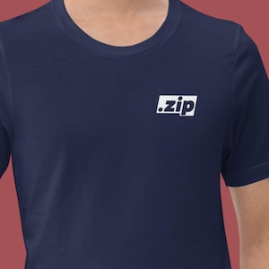 Puede incluir: Camiseta azul marino con el texto blanco ".zip" en un rectángulo blanco en el pecho. La camiseta está hecha de un material suave y tiene mangas cortas.