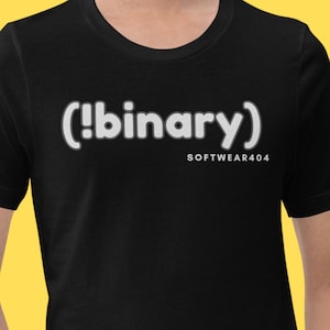 Peut inclure: T-shirt noir avec le mot "(!binary)" en lettres blanches soulignées. En dessous, le texte "SOFTWARE404" est écrit en plus petit. Le t-shirt est de style col rond.