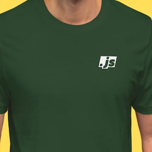 May include: A dark green t-shirt with a white square logo on the upper left chest. The logo features the letters ".js" in a stylized font. The shirt has short sleeves and a crew neck.