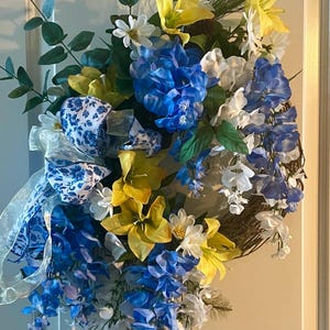Decoración de puerta azul con corona de verano de glicina azul y blanca