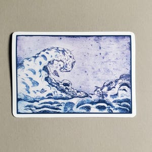 May include: A sticker featuring a blue and white illustration of a large ocean wave. The wave is depicted with intricate detail, with a cloudy sky in the background. The sticker has a white border.