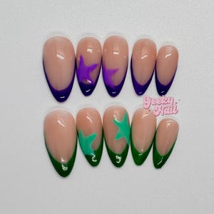 May include: Set of ten artificial nails with a nude base. Five nails have a purple French tip with a purple star design. The other five nails have a green French tip with a green star design. The text "Geeky Nail" is in the image.