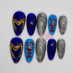 May include: A set of ten artificial nails in various designs. The nails are oval-shaped and feature a mix of blue, silver, and light blue colors. Some nails have a design with a yellow and orange pattern, while others display the letters "SON" in red.